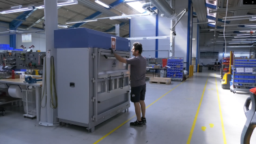 Homme aux cheveux foncés utilisant une grande presse à balles chez Hydra Specma